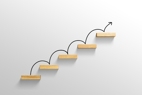 Five wooden steps with an arrow drawn to symbolizing the steps of a ladder