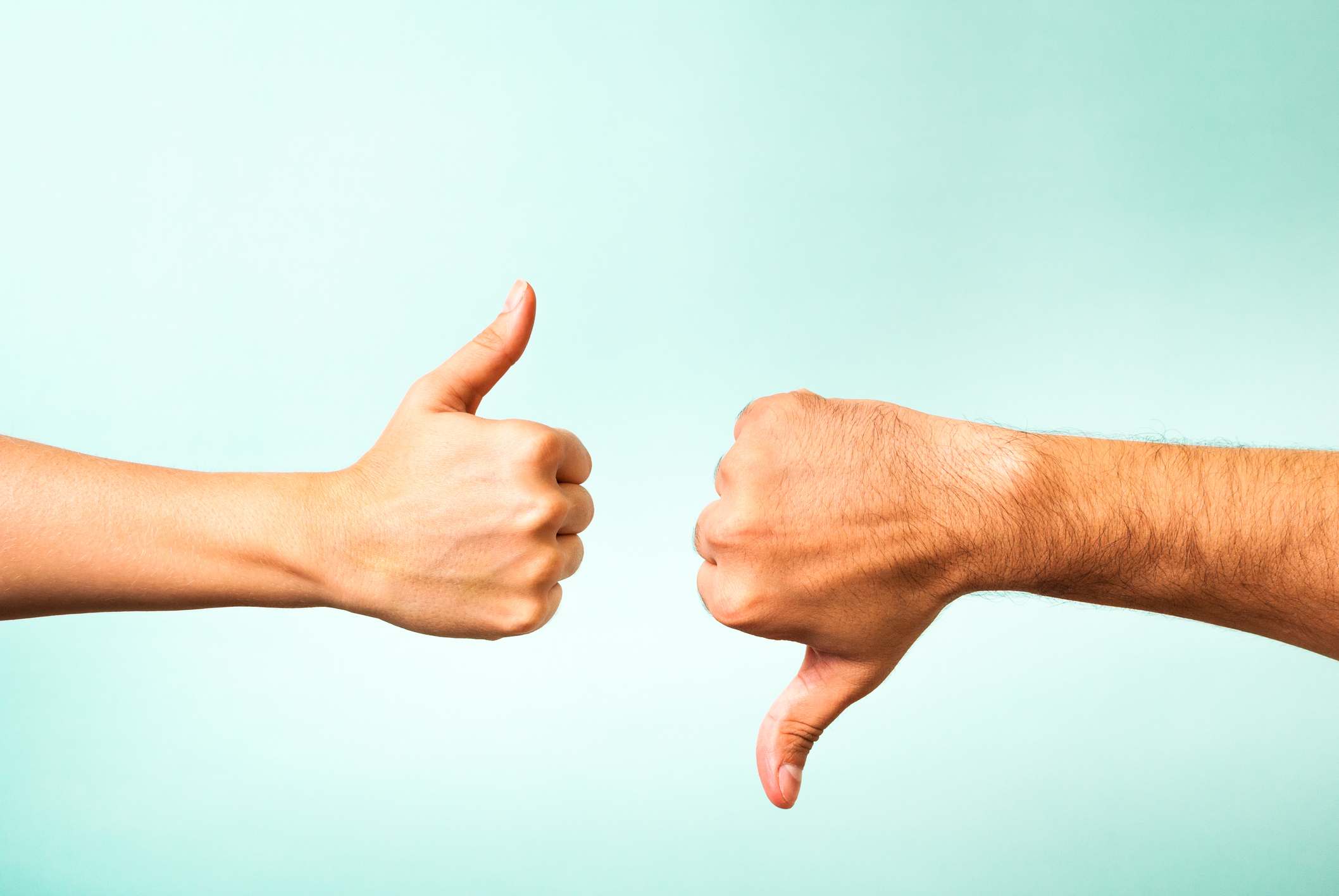 Two hands, one showing a thumbs up and one showing a thumbs down. 